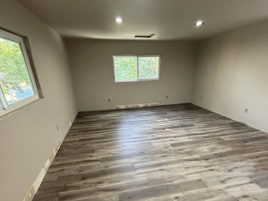 Attic converted into a finished room with plank flooring, a new window and recessed lighting